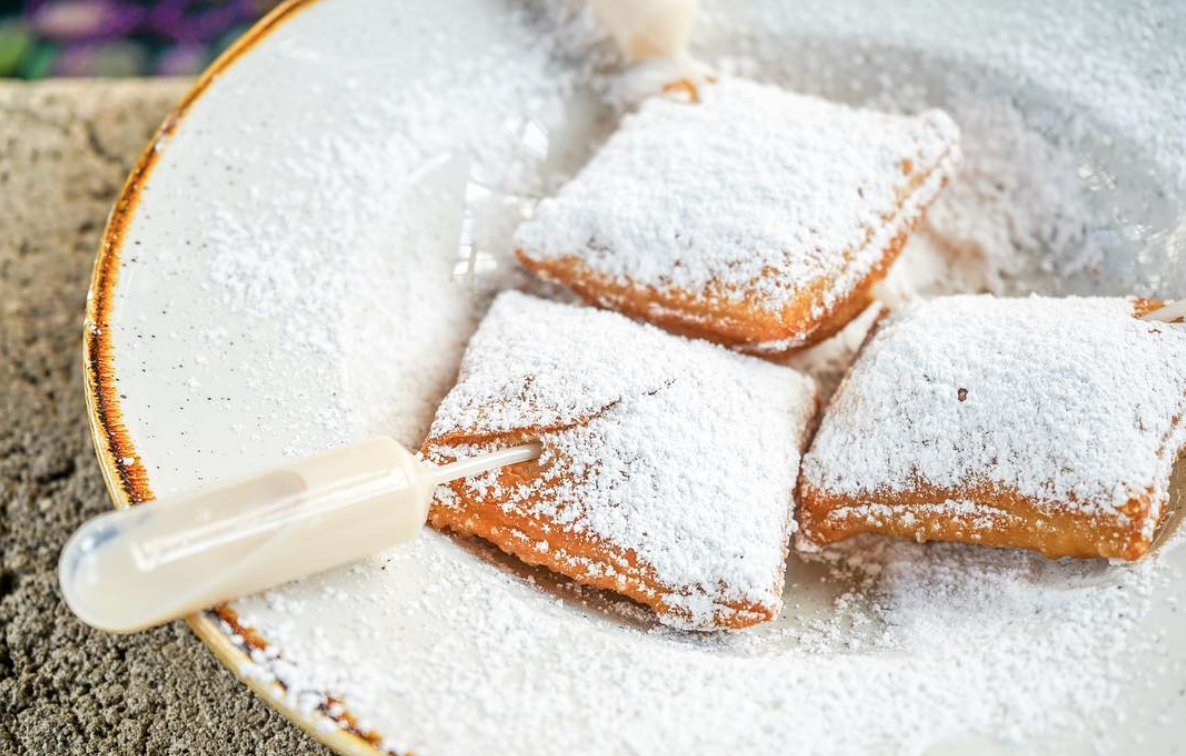 Three Baton Rouge Beignets on a plate with white frosting and boozey plastic pipettes