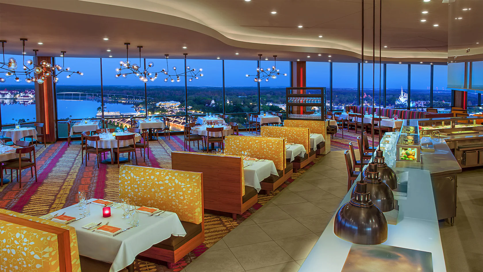 Internal picture of California Grill Restaurant Disney World. Low hanging lights, large full length windows overlooking Disney World