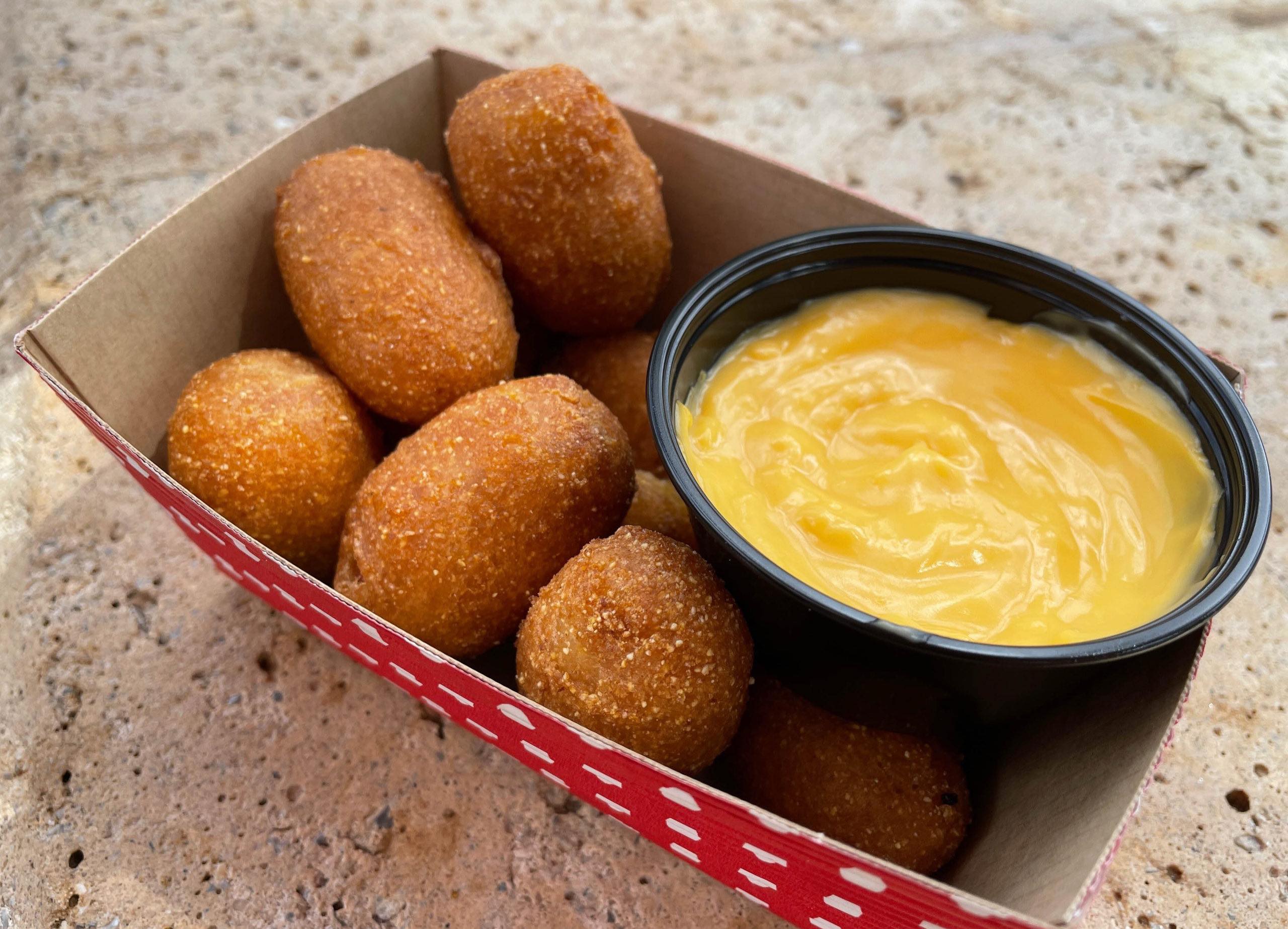 A cardboard tray of Casey's corn dog nuggets with a plastic dish of cheese sauce.