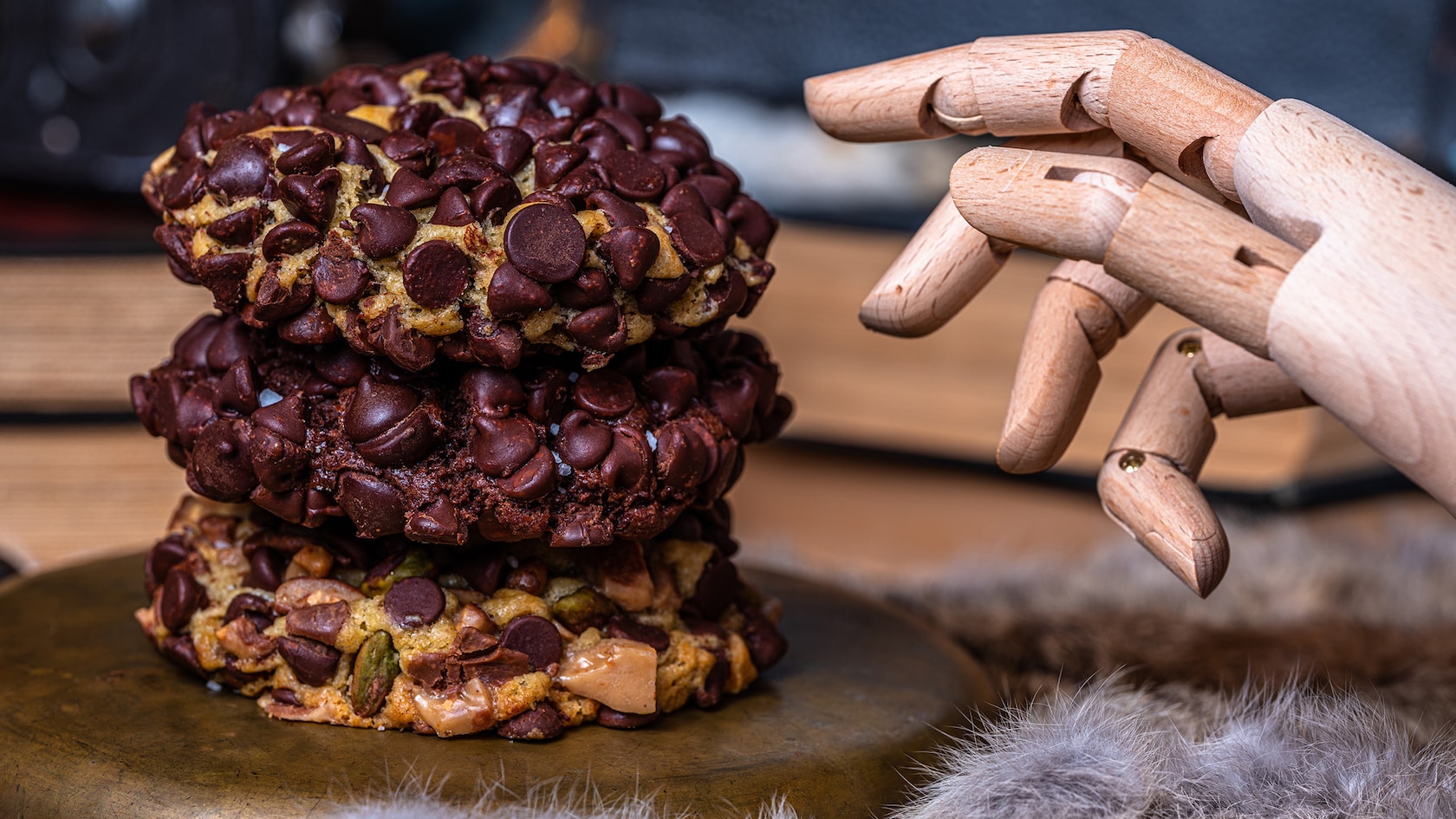 Picture of a stack of chocolate chip cookies with a wooden hand reaching towards them.