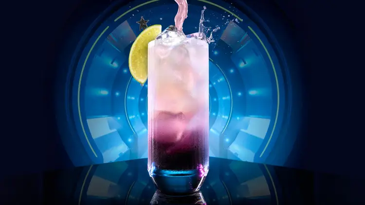 Picture of purple stargarita drink with a slice of lime on a spaceship like background.