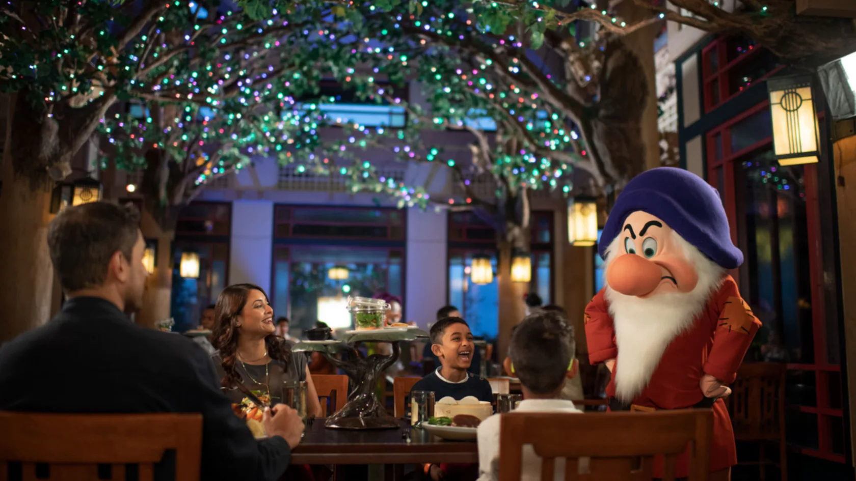 Internal picture of Story Book Dining Restaurant at Disney World. Family laughing at Grumpy character.